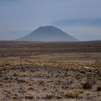 A vocano in the distance, with a scrub dotter desert in the foreground